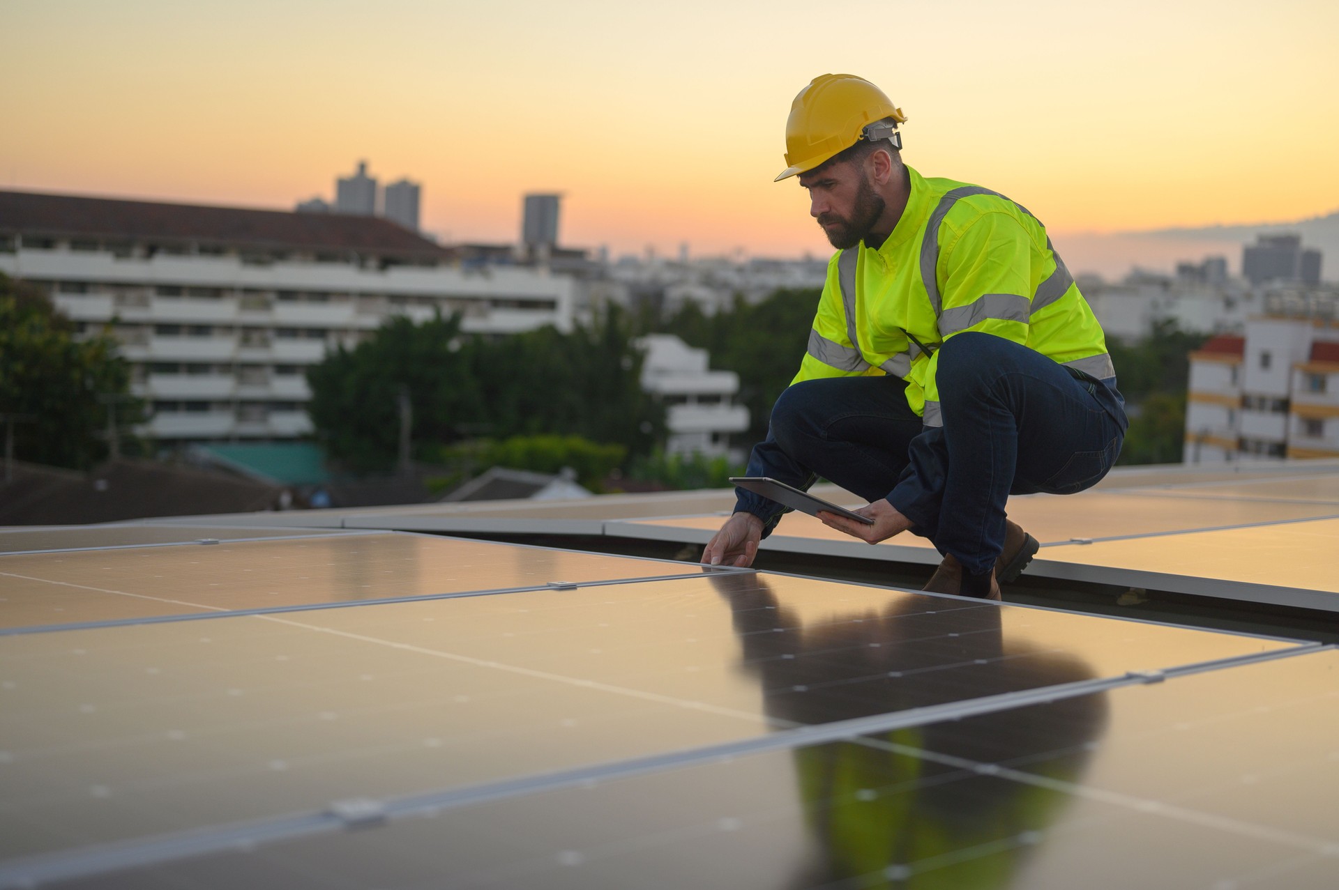 Male engineer works installing solar panels on the roof. Engineer or worker working on solar panels or photovoltaic cells on the roof of a business building.
